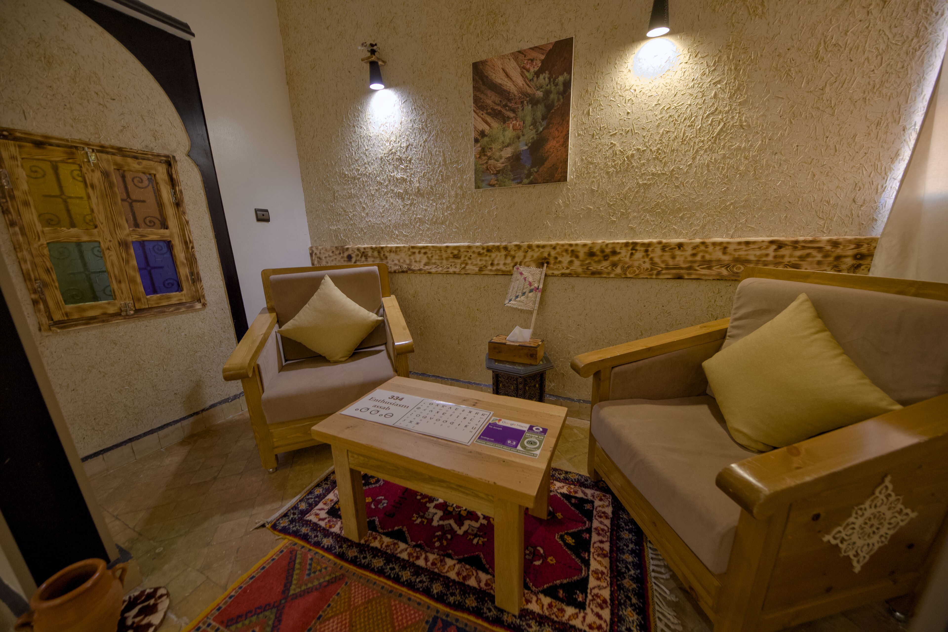 A cozy living room with a wooden sofa, armchairs, and a small table with a placemat.