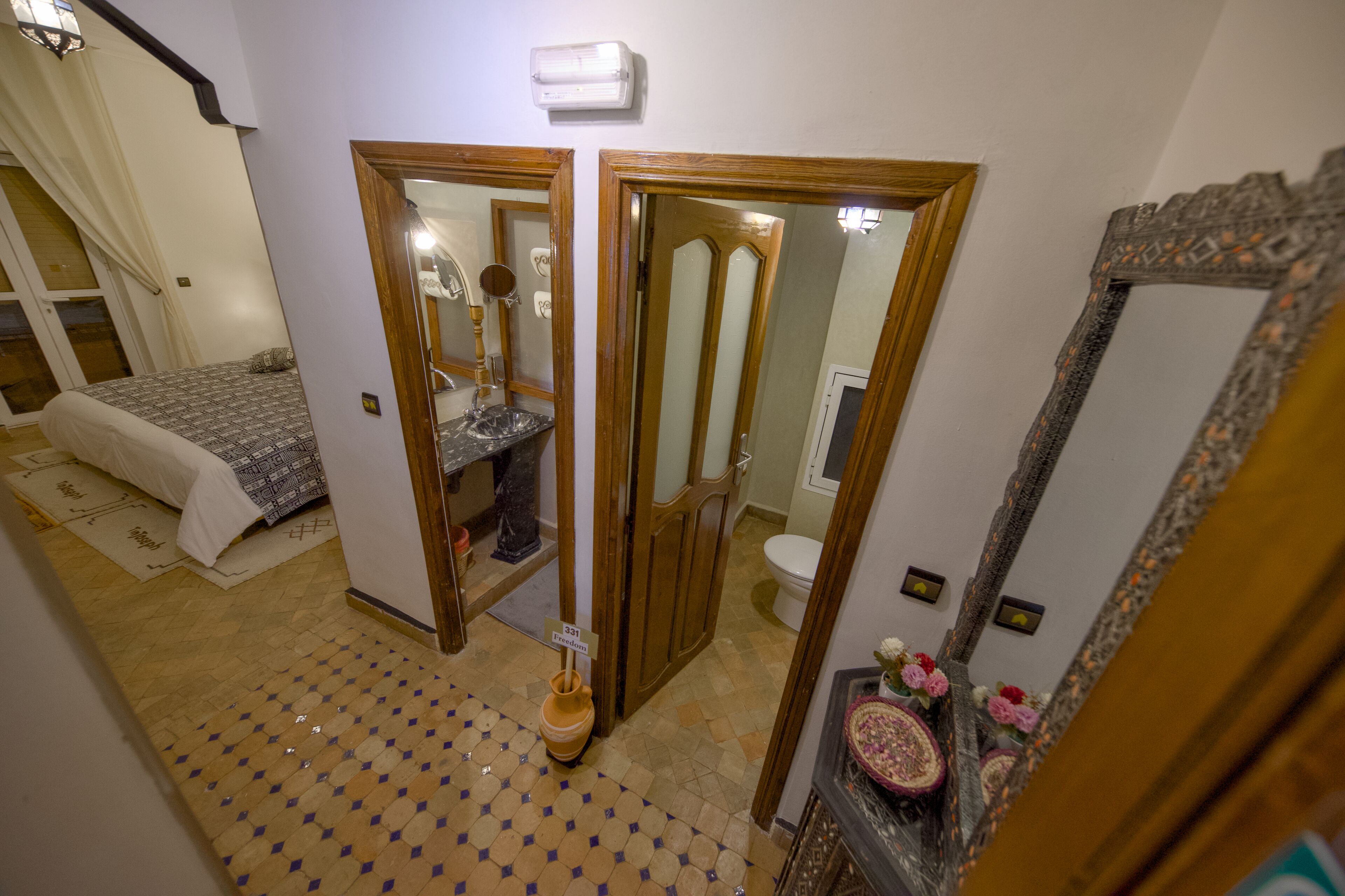 Una habitación con cama, baño y espejo.