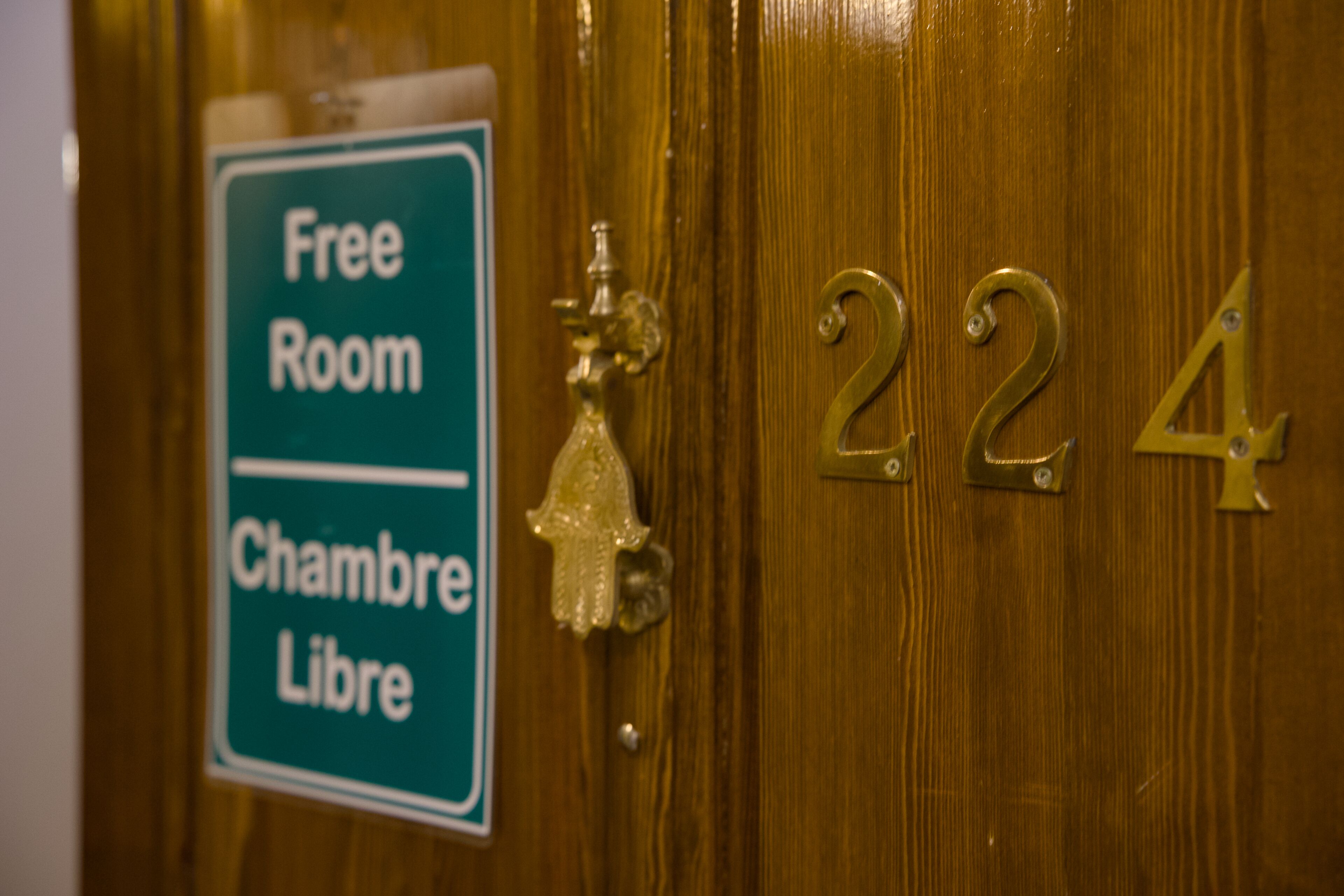Una porta con una targa di ottone con il numero "224" e un cartello che indica "Camera Gratuita" in francese.