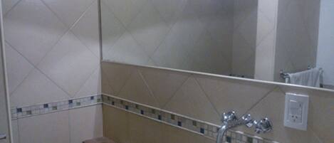 Un baño con un lavamanos blanco, un espejo y una pared de azulejos.