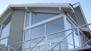 Un bâtiment doté d’une grande fenêtre à plusieurs vitres et d’un balcon avec une balustrade blanche.