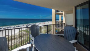 A balcony with a view of a beach and ocean. There are two Adirondack chairs and a small table. - ~ Two Bedroom @ Phoenix V (Orange Beach)