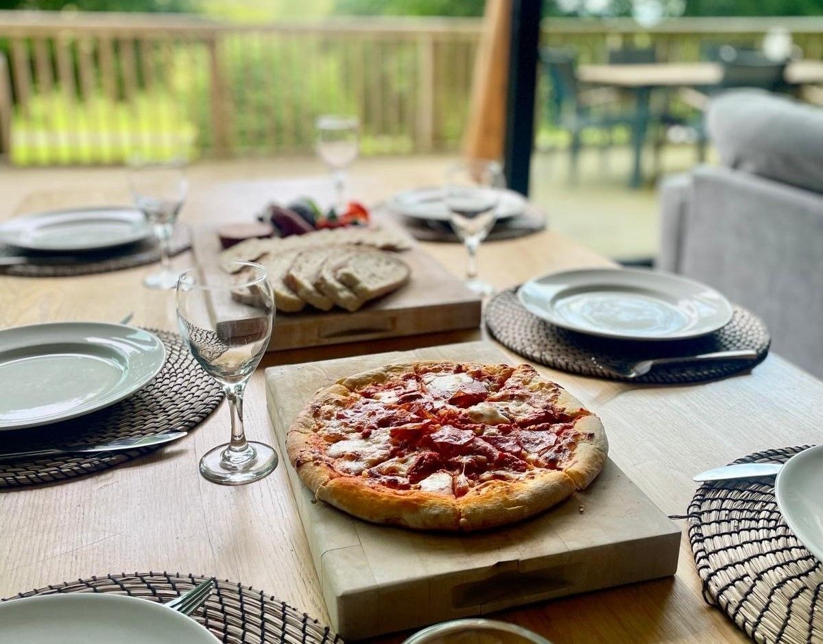 Ein Esstisch mit Tellern, Besteck und einer Pizza.