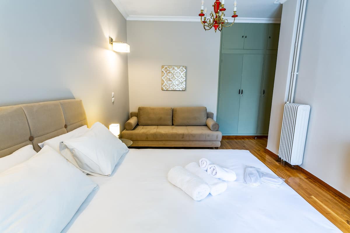 A hotel room with a bed, a sofa, and a radiator.