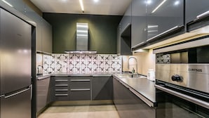 Een moderne keuken met roestvrijstalen apparatuur, donkere kastjes en een betegelde achterwand met patroon.