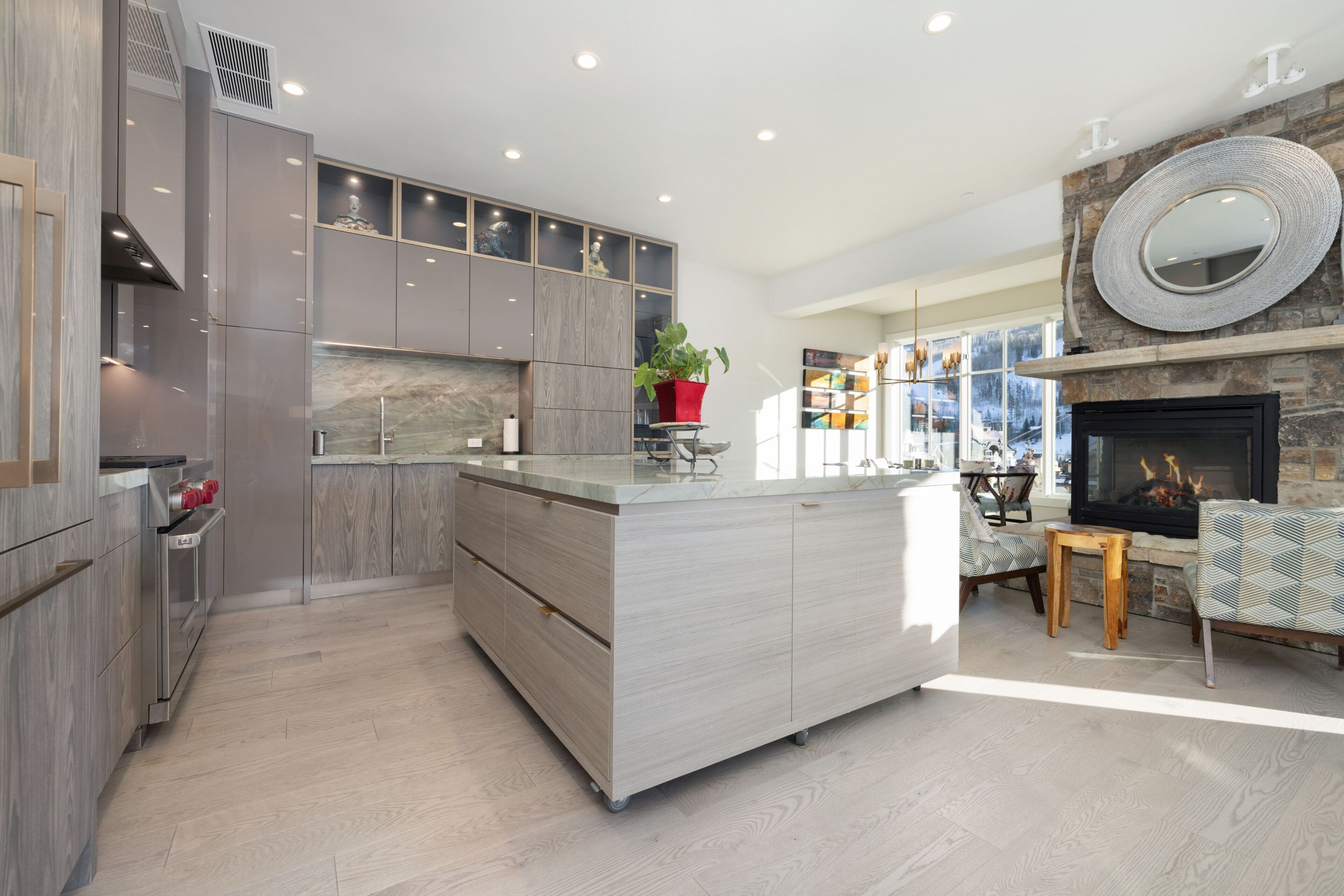 A modern kitchen with a central island, built-in cabinets, and a stone fireplace.