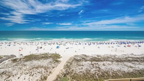 Een strand met heldere lucht, zandstrand en strandparasols.