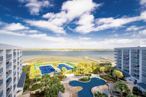 Un hotel con piscina, canchas de tenis y vista al mar.