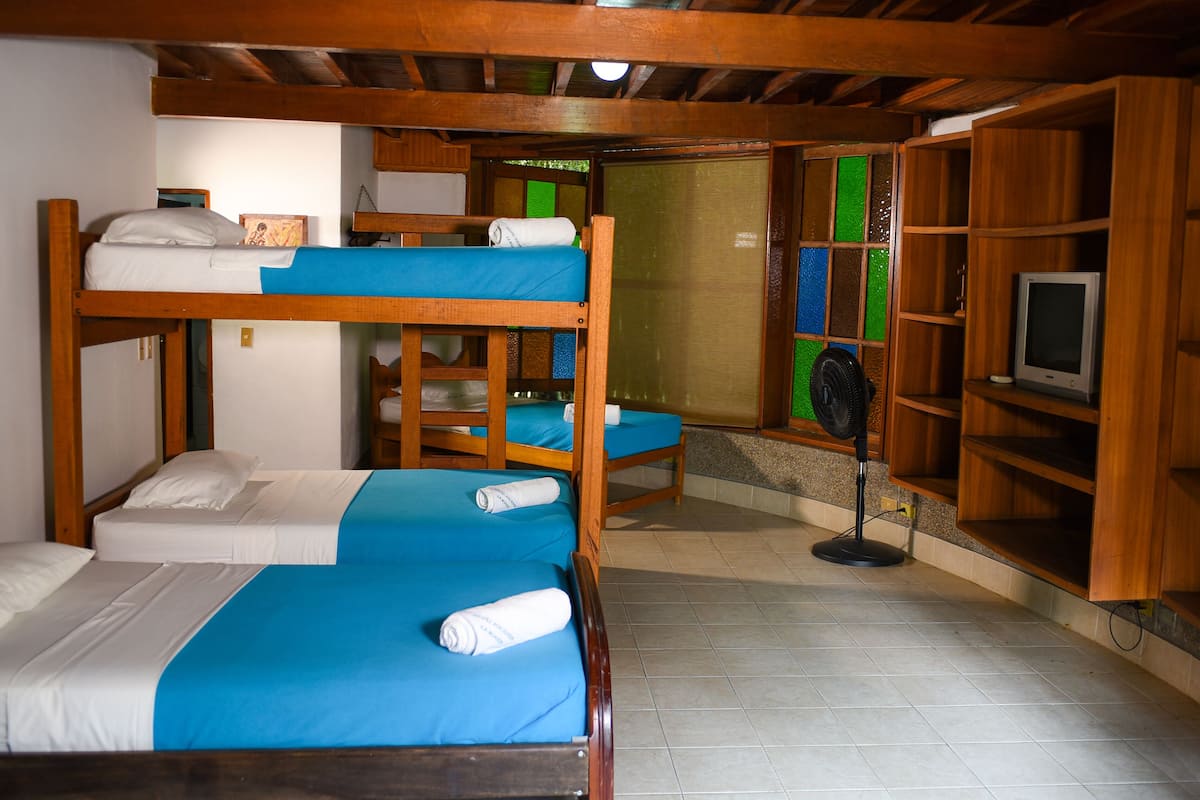 Una habitación con literas, un ventilador y estantes de madera.