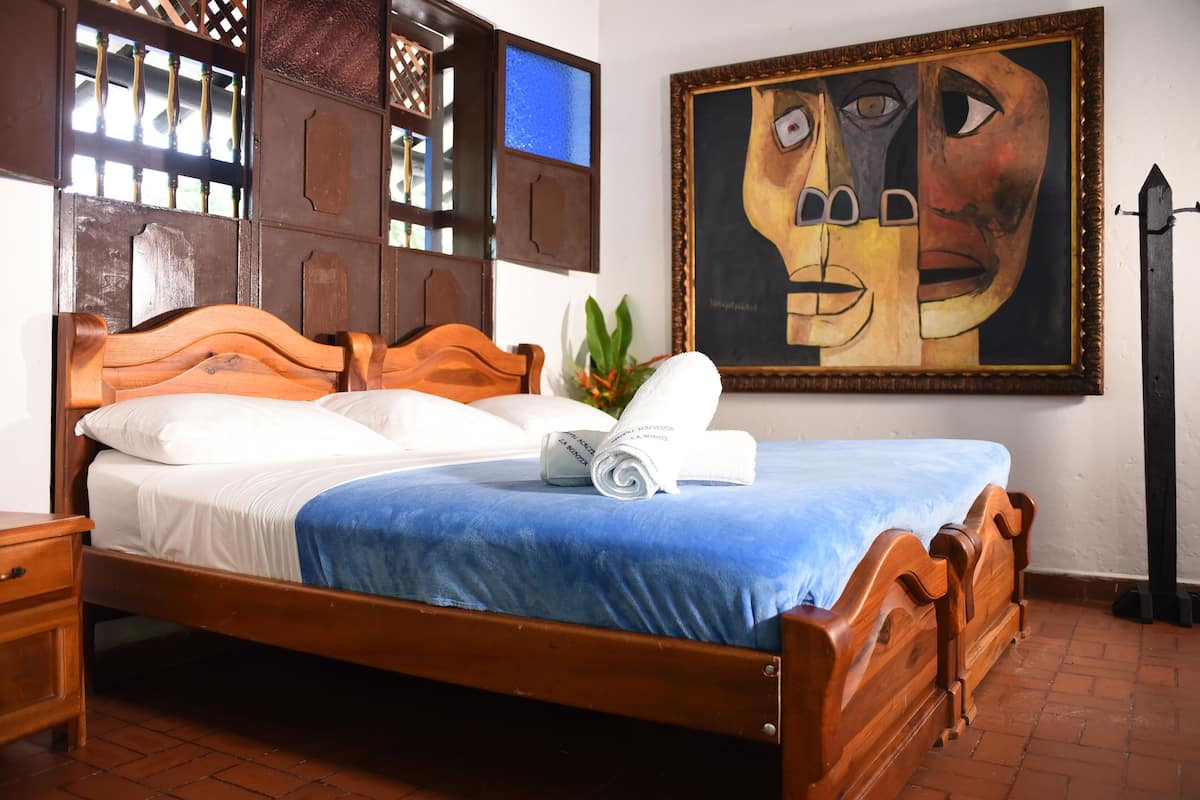 Una cama de madera con colcha azul, una almohada blanca y una toalla enrollada.