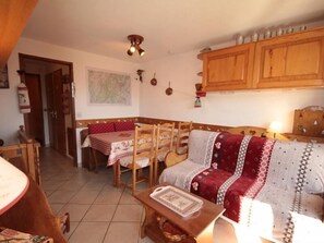Ein gemütliches Wohnzimmer mit einer Couch, einem Esstisch mit Stühlen, Holzschränken und einem Deckenventilator.