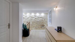 A hallway with a stone wall, a wooden bench, and a door. - Sweett | Sentier II - Four Bedroom Apartment, Sleeps 9 (Paris)