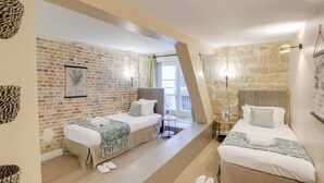A hotel room with two beds, a brick wall, a stone wall, and a balcony with a view. - Sweett | Sentier II - Four Bedroom Apartment, Sleeps 9 (Paris)