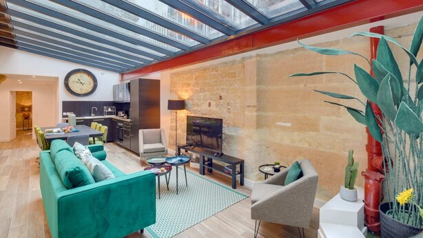 A spacious living area with a high ceiling, a modern kitchen, and a cozy seating area. - Sweett | Sentier II - Four Bedroom Apartment, Sleeps 9 (Paris)
