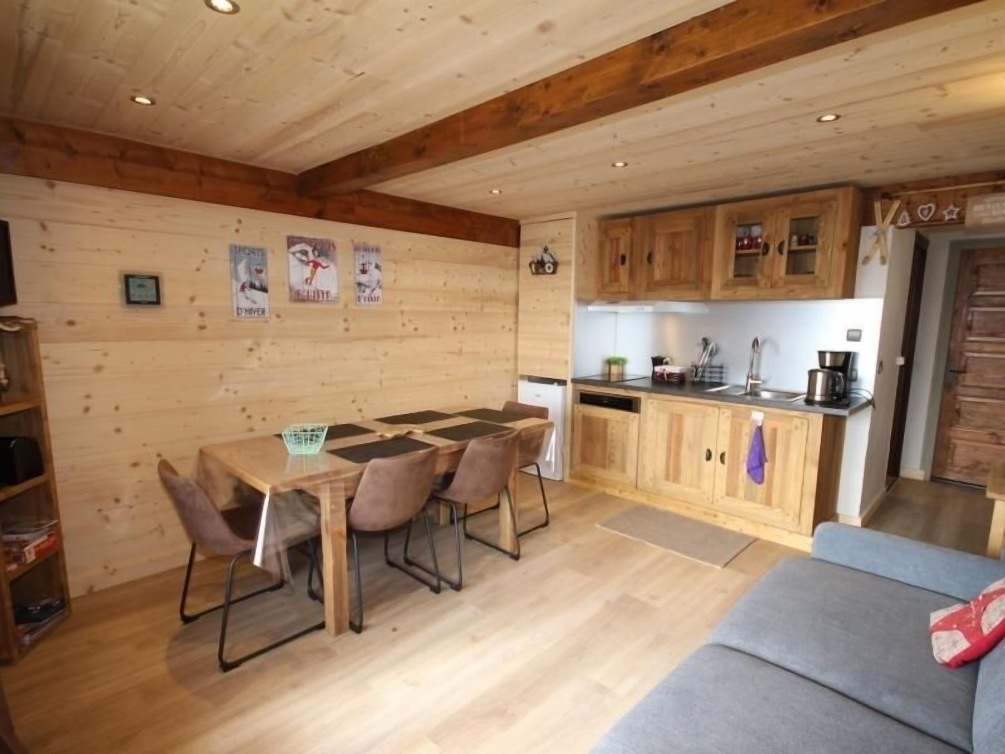 A cozy cabin-style kitchen with wooden cabinets, a dining table with chairs, and a sofa.