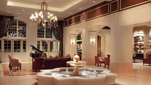 A grand lobby with a fountain, piano, and elegant chandeliers.
