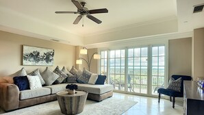 A spacious living room with a large window, a ceiling fan, and a view of the outdoors.