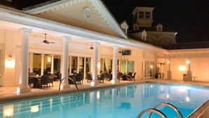 A swimming pool with a covered area and outdoor seating.