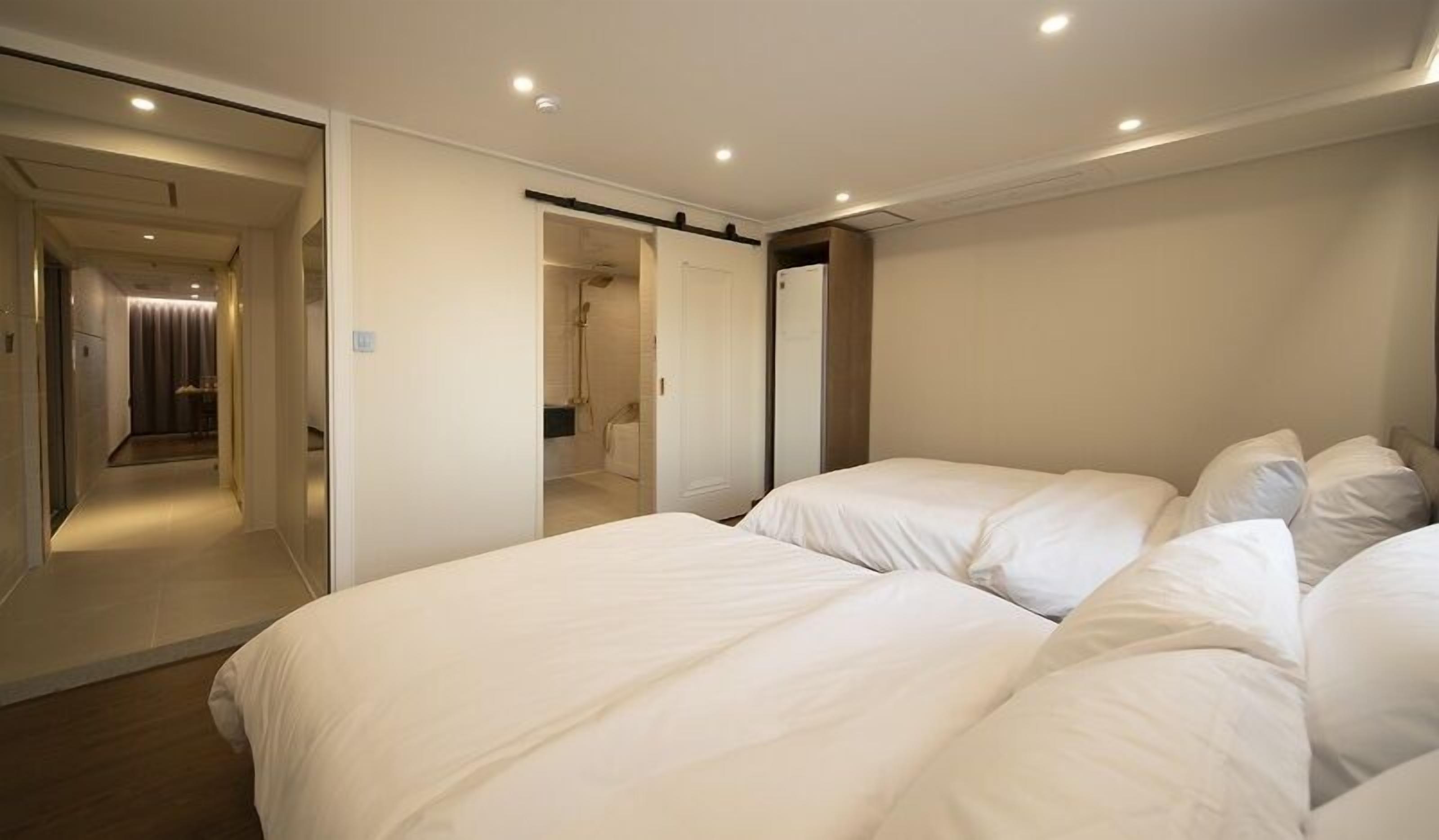 Une chambre d’hôtel avec deux lits, un dressing et une salle de bain avec douche et toilettes.