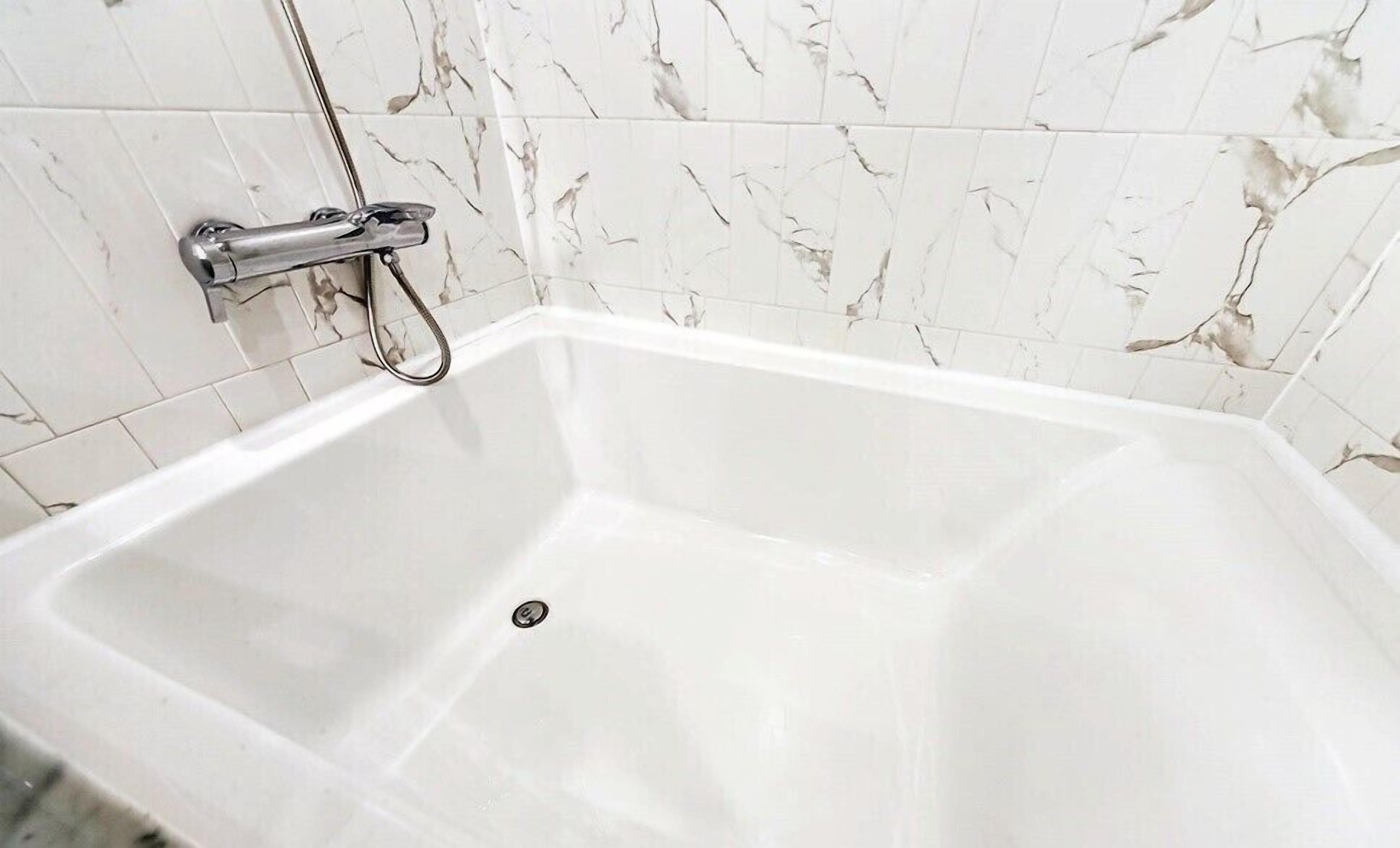 Una bañera blanca con grifo de cromo y desagüe.