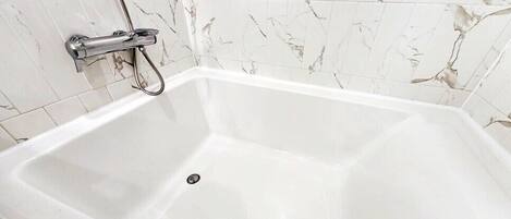 Una bañera blanca con grifo de cromo y desagüe.