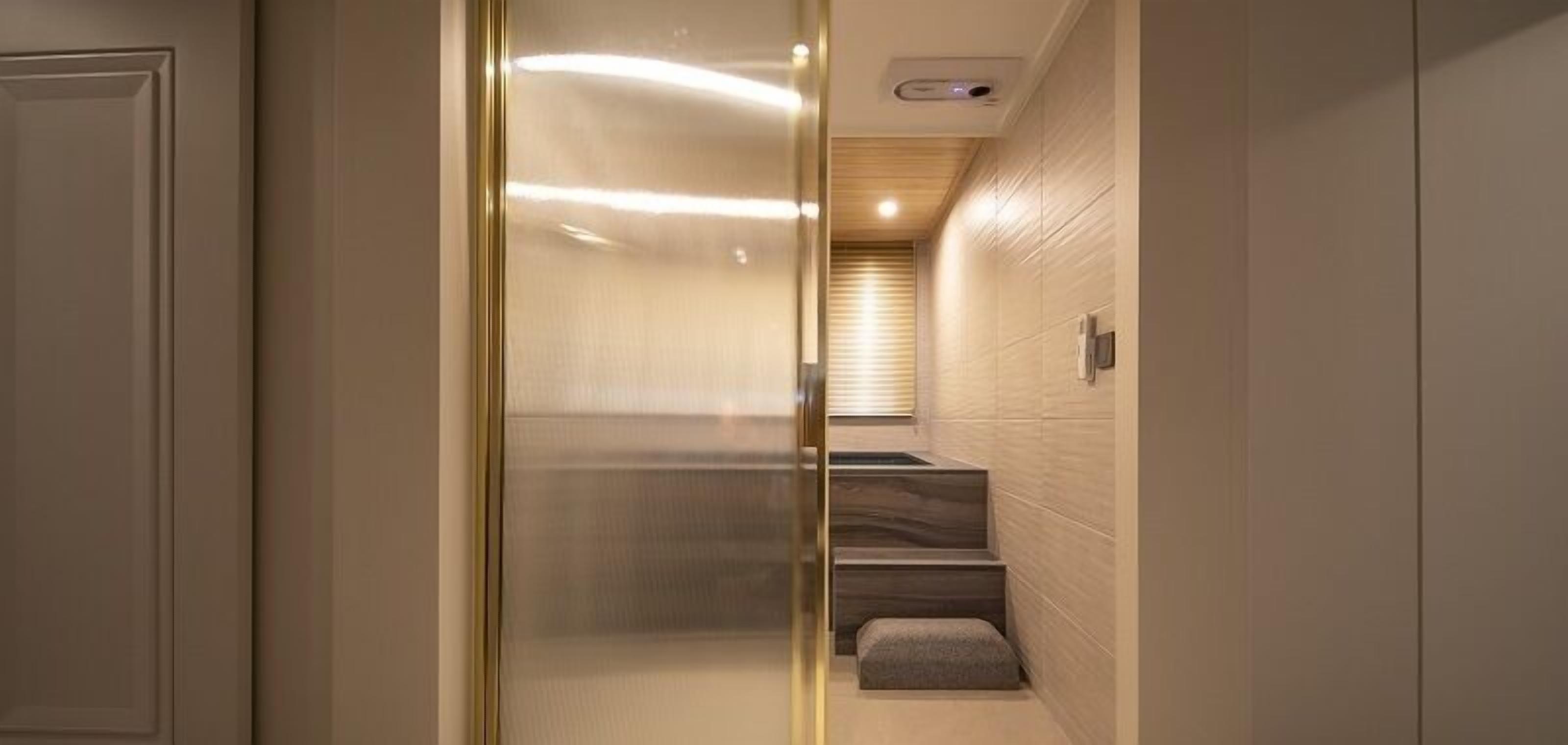 A modern bathroom with a glass partition, a wooden bench, and a built-in shower area.