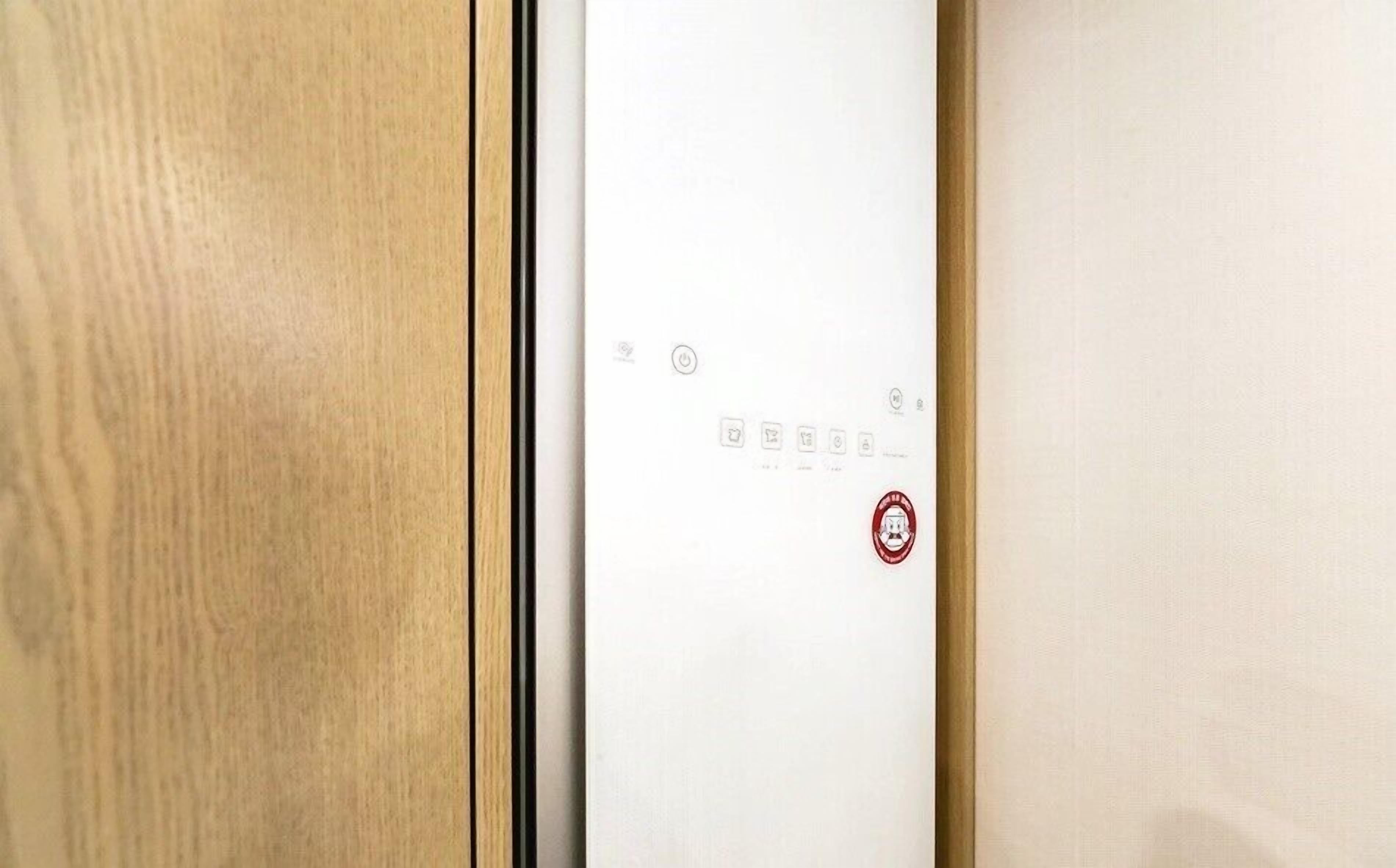 Una puerta con un panel de control que incluye un botón de encendido y varios iconos de funciones.
