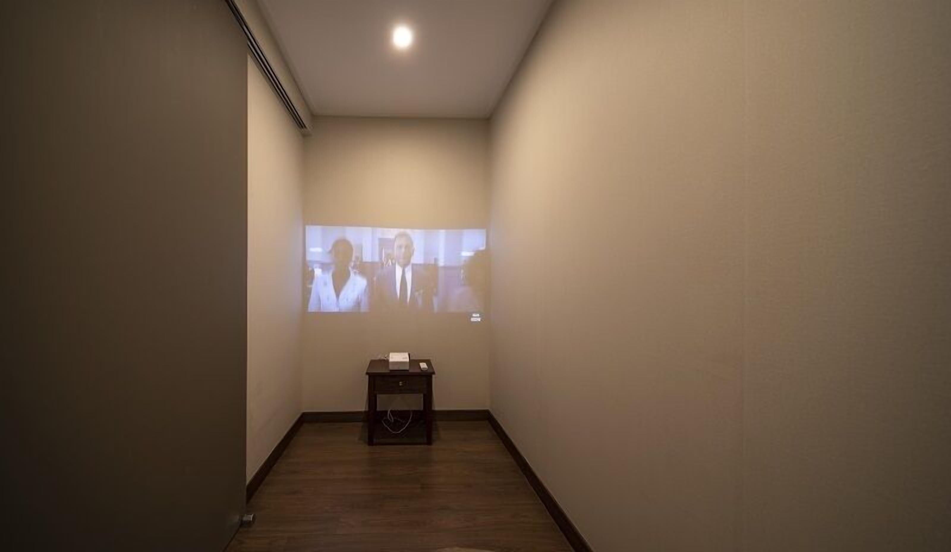 A hallway with a projection screen displaying two people.