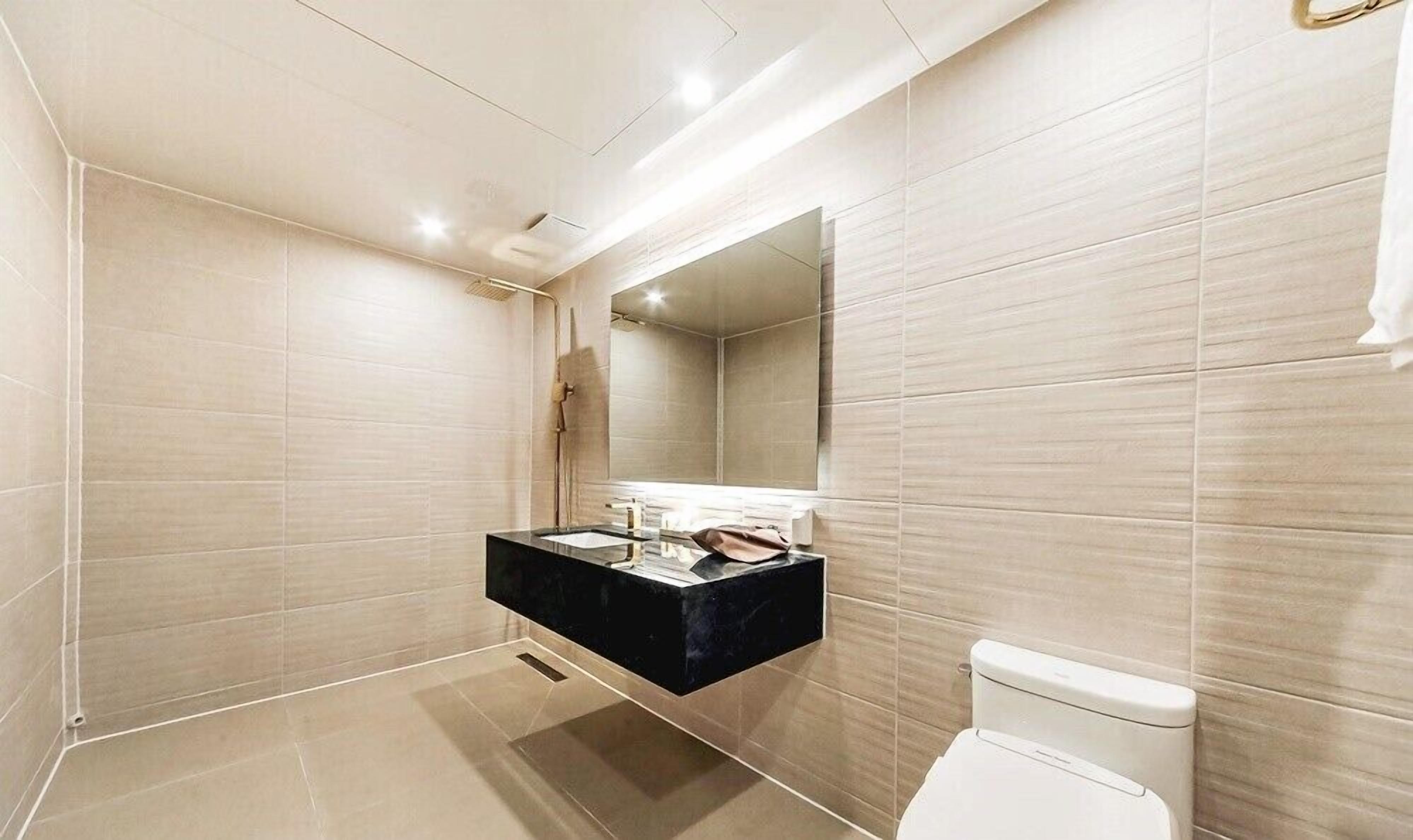 Een moderne badkamer met een zwart wastafelmeubel, een grote spiegel en een toilet.