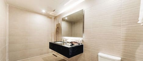 A modern bathroom with a black vanity, a large mirror, and a toilet.