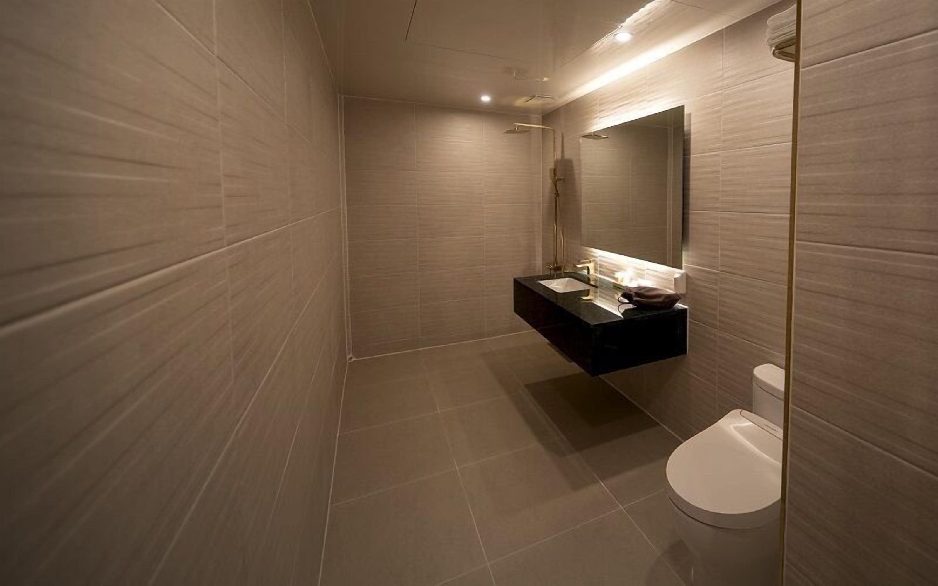 Un baño moderno con lavamanos integrado, inodoro y un espejo grande.