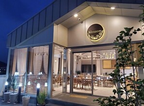 A modern restaurant with a glass facade, wooden interior, and a circular sign with 'blossom' written on it. - Centro Hotel (Chilgok)