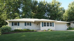 A single-story house with a front porch, a garage, and a well-maintained lawn. - Five Bedrooms and a Great Location (Sioux Falls)