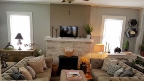 Un salon avec une cheminée, deux canapés, un téléviseur et des objets de décoration.