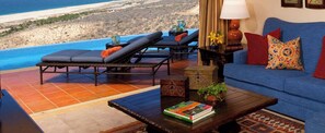 Ein luxuriöses Wohnzimmer mit Blick auf die Baja California Halbinsel, ausgestattet mit einer Couch, Lounge-Sesseln und einem Couchtisch mit Büchern.