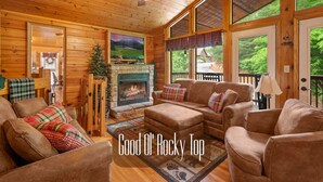 A cozy log cabin interior with a fireplace, comfortable seating, and large windows offering a view of the outdoors. - Best Location/HotTub/Resort Pool/Game Rm/Fast WiFi
Dollywood 2 minutes away! (Sevierville)