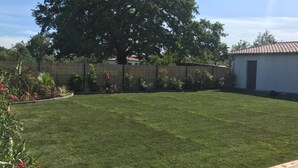 A backyard with a well-maintained lawn, a wooden fence, and a small shed. - Pleasant house on the Arcachon basin (La Teste-de-Buch)