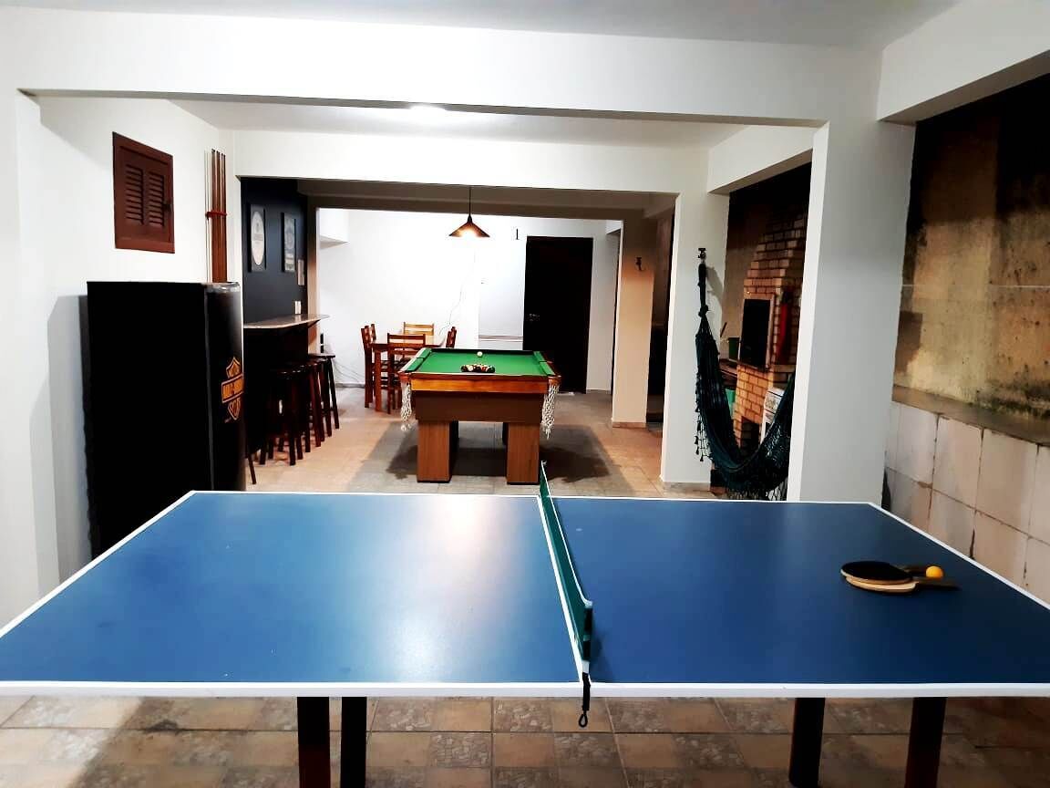 Ett rum med ett bordtennisbord, ett biljardbord och en matplats med stolar och ett bord.