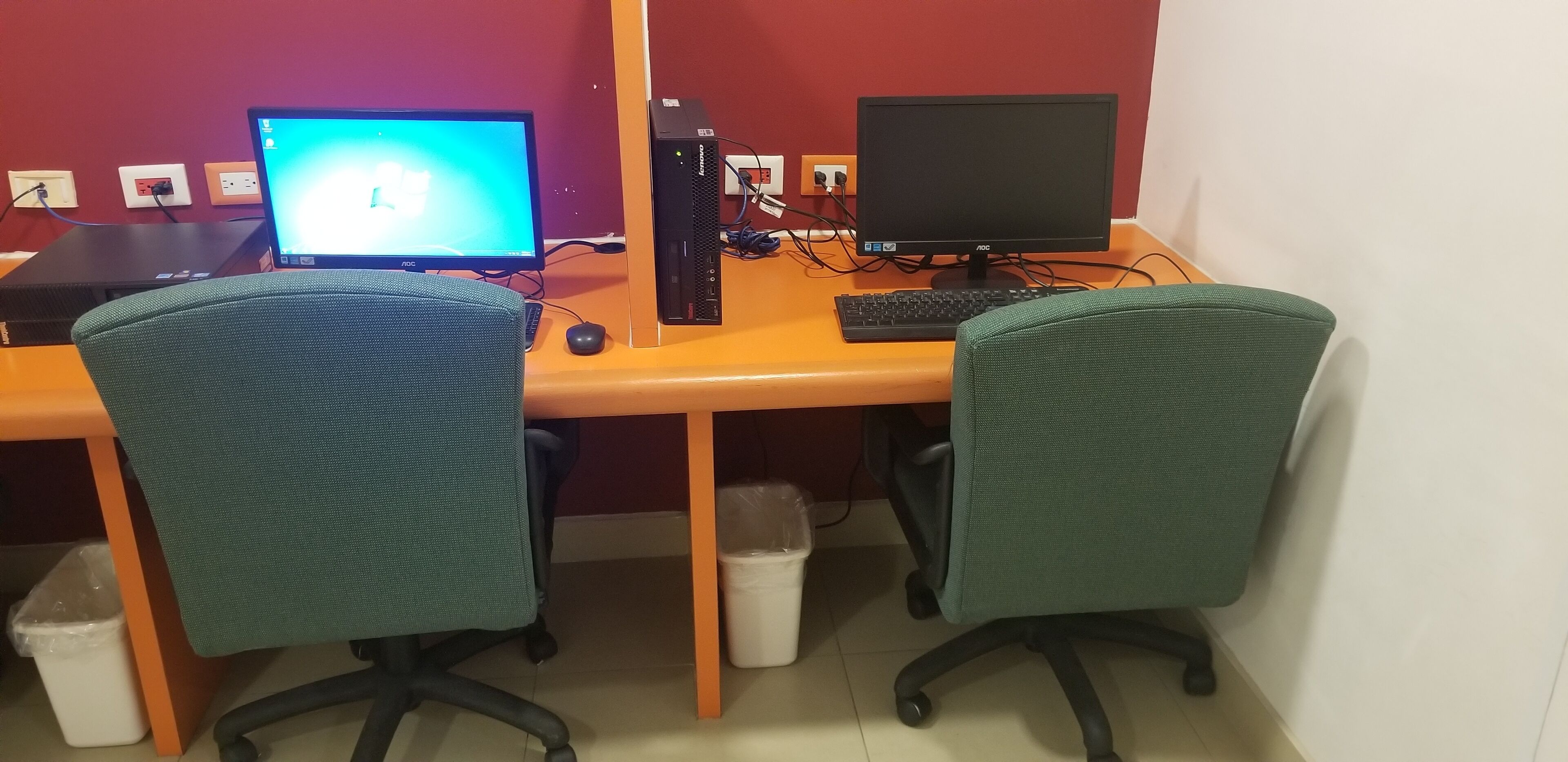 A workspace with two computers, a keyboard, and two office chairs.
