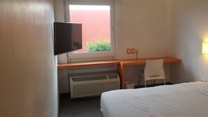 A hotel room with a bed, a desk with a chair, a television, a window, and a wall-mounted light. - Hotel Tecnologico Norte (Chihuahua)