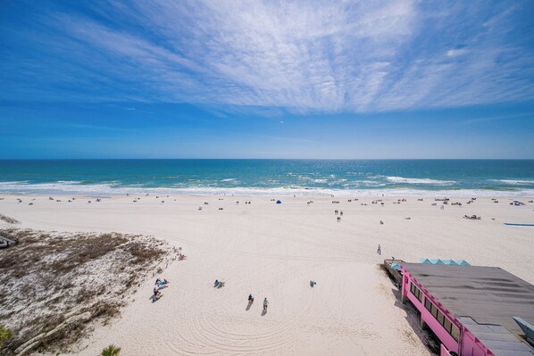 A beach with a clear sky, sandy shore, and a few people.