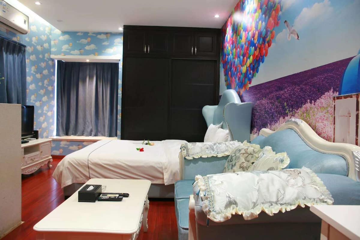 A hotel room with a bed, a desk, a TV, and a mural on the wall.