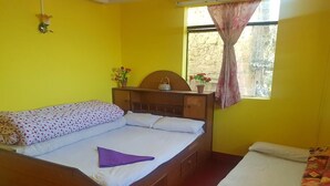 A room with a wooden bed, a smaller bed, a window with curtains, and a wall-mounted lamp. - Nagarkot Community Homestay (Mahamanjushree Nagarkot)