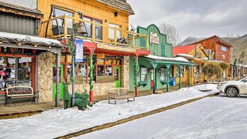 A snow-covered street with colorful buildings, including a restaurant and a pizza place.