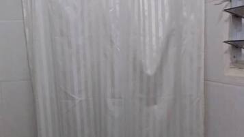 A bathroom with a toilet, a shower curtain, and a tiled wall.