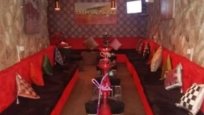 Ein Restaurant mit roter Sitzpolsterung, einem zentralen Raucherbereich und Wandverkleidung mit Muster.