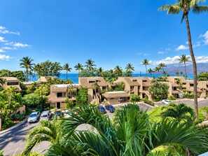 A coastal hotel with multiple buildings, a parking lot, and a clear view of the ocean.
