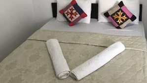 A bed with two pillows, a rolled-up towel, and a framed picture on the wall. - Atozee Airport villa (Seeduwa - Katunayake)
