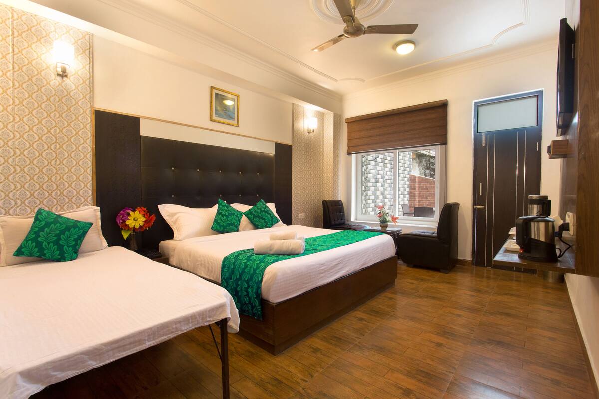 A hotel room with two beds, a ceiling fan, a window with a view, and a coffee machine.
