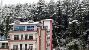 A multi-story building with a sign for Hotel Shivani International. - Hotel Shivani International (Dharamshala)